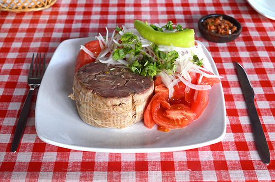 Corte de carne a la parrilla servido con ensalada, sobre el mantel a cuadros.