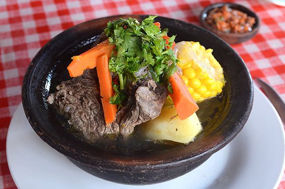 Cazuela servida en fuente de greda, con choclo, zapallo y papa.