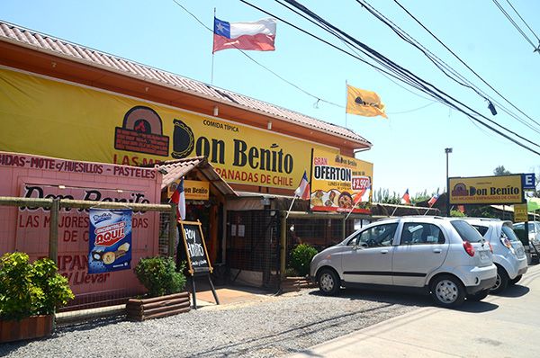 Fachada amarilla de Don Benito sobre Camino Lonquén, con banderas y la señalética de la casa.