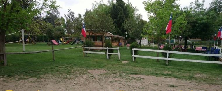 Zona de juegos infantiles con resbalín y columpios sobre pasto.